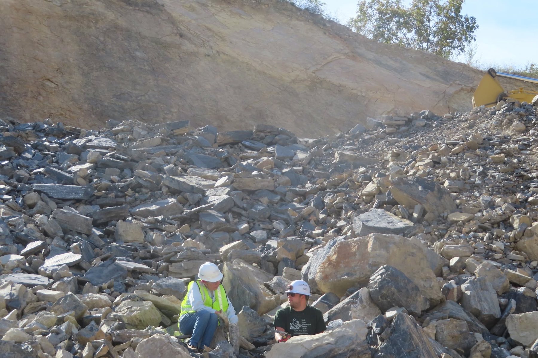 Club members in hard hats and hi-vis vests collecting specimens at a limestone quarry